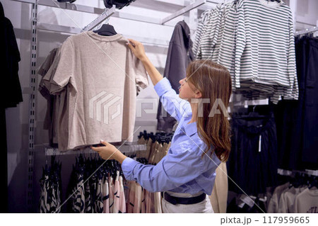 Mother and daughter shopping. A middle-aged plus-size woman and a teenage girl choose clothes and decor in a store. Mother and daughter shopping. A middle-aged plus-size woman and a teenage girl choose clothes and decor in a store. 117959665