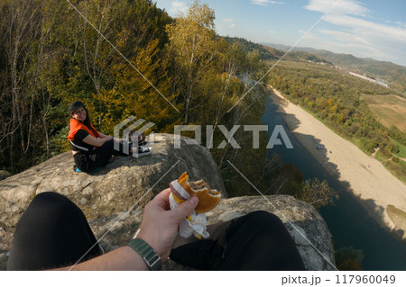 pov Eating Burger at Cliff with Mountain River View 117960049