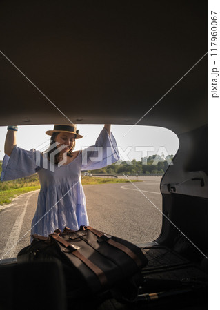 Smiling Woman with Backpack by Car on Scenic Road 117960067