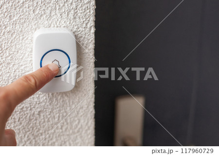 Hand Pressing White Doorbell with Blue Ring Hand Pressing White Doorbell with Blue Ring 117960729