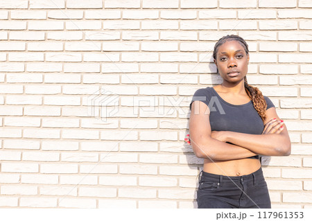 A Confident Woman Posing Gracefully Against a Rugged Brick Wall in an Urban Setting 117961353