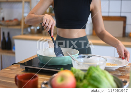 Cropped shot of young woman in sportswear preparing a nutritious breakfast or snack at kitchen counter 117961947