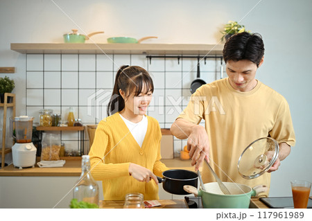 An affectionate young couple couple sharing a joyful cooking experience at kitchen counter An affectionate young couple couple sharing a joyful cooking experience at kitchen counter 117961989