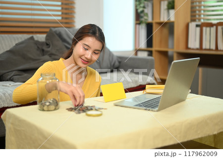 Happy young woman organizing or counting the money. Saving money and financial responsibility concept 117962009