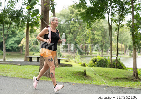 Senior woman walking briskly in scenic park setting 117962186