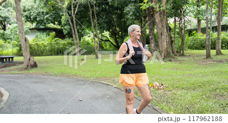 Senior woman enjoying a walk in lush park environment Senior woman enjoying a walk in lush park environment 117962188