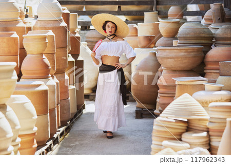 Young woman, poised with fan, stands confidently in pottery yard, bridging eras of Spanish tradition and elegance of modern tourism. Concept of harvesting. Young woman, poised with fan, stands confidently in pottery yard, bridging eras of Spanish tradition and elegance of modern tourism. Concept of harvesting. 117962343