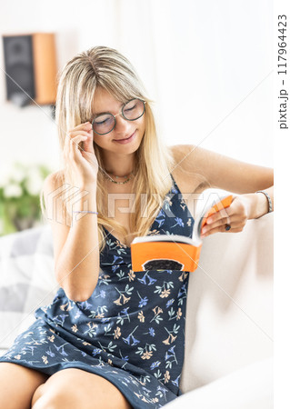 A young lady is reading a book and wearing prescription glasses. 117964423