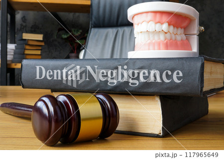 Model of a jaw and book with the inscription Dental negligence. Model of a jaw and book with the inscription Dental negligence. 117965649