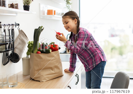 Young girl examining fresh vegetables in kitchen Young girl examining fresh vegetables in kitchen 117967619