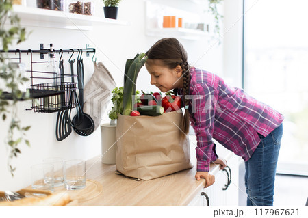 Young girl examining fresh vegetables in kitchen 117967621