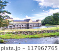 青空の下に広がる建物と池 117967765