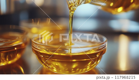 Pouring golden oil into small bowls on a kitchen counter during a cooking session 117968215