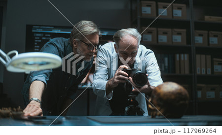 Two archaeologists photograph fossil skull with professional camera 117969264