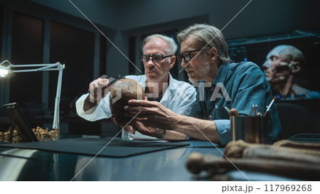 Two archaeologists measures fossil skull, use tablet computer Two archaeologists measures fossil skull, use tablet computer 117969268