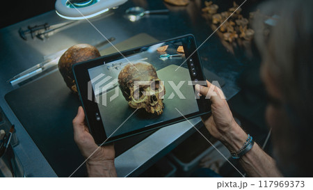 Archaeologist takes photo of prehistoric extinct human skull using tablet computer 117969373
