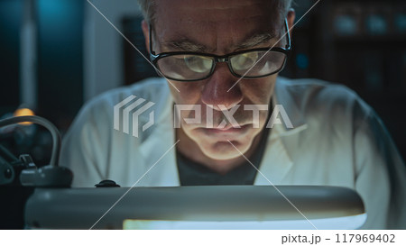 Scientist works in archaeological lab at night, takes measurements of fossil bone 117969402