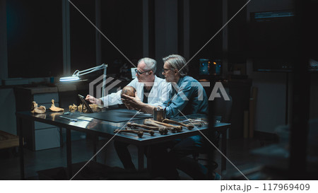 Two archaeologists take measurements of ancient human skull, use tablet computer Two archaeologists take measurements of ancient human skull, use tablet computer 117969409