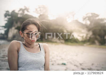 海辺でサングラスをかけて黄昏る若い女性 117969624