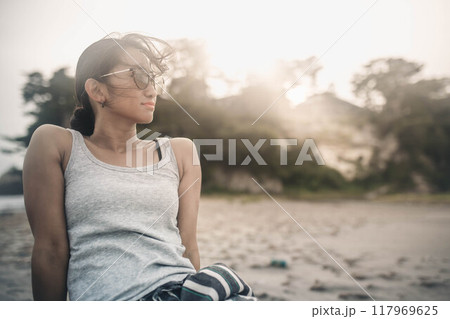 海辺でサングラスをかけて黄昏る若い女性 117969625