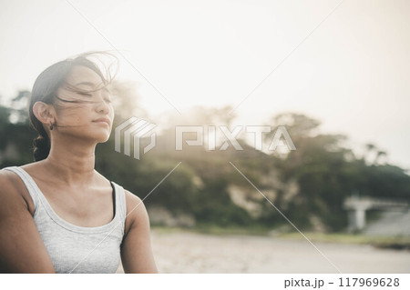 海辺でサングラスをかけて黄昏る若い女性 117969628