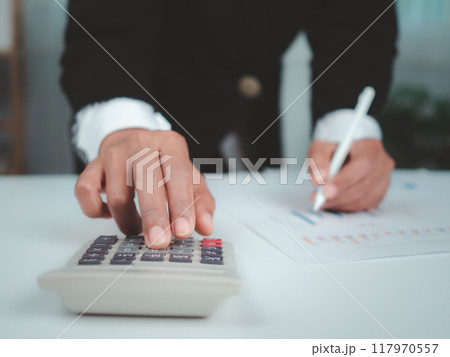 Businesswoman in black suit working on laptop computer and tablet and calculator, Hand Hands touch on tablet at office with dark background, Online working, Close up, Copy space. 117970557