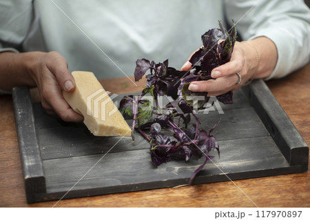 Hands preparing salad, holding cheese and basil sprigs. Hands preparing salad, holding cheese and basil sprigs. 117970897