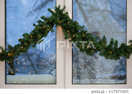 Part of a plastic window decorated with a Christmas garland. 117971003