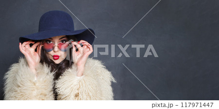 Cheerful woman with red lips make-up and long wavy hair wearing blue hat  117971447