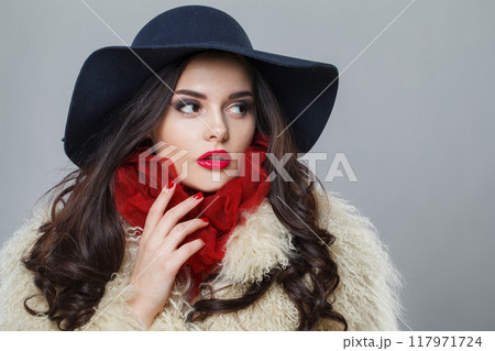 Elegant fashion model woman in blue classic hat and white fur coat posing indoor 117971724