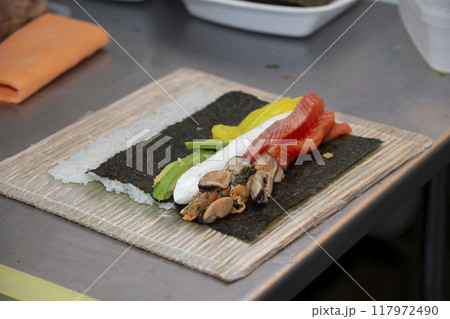 The process of preparing sushi rolls in the kitchen of a bar or sushi restaurant. 117972490