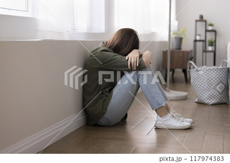 Teen girl crying seated on floor, suffers from bullying 117974383