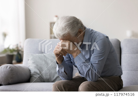 Depressed man sit on sofa, crying, covering face with hands Depressed man sit on sofa, crying, covering face with hands 117974516