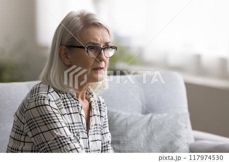 Mature woman deep in sad thoughts sit alone at home Mature woman deep in sad thoughts sit alone at home 117974530