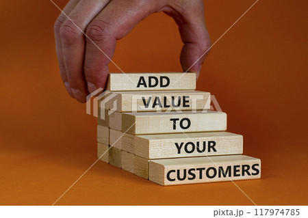 Add value to your customers symbol. Concept words 'Add value to your customers' on wooden blocks on a orange background, copy space. Businessman hand. Business, customers value concept. Add value to your customers symbol. Concept words 'Add value to your customers' on wooden blocks on a orange background, copy space. Businessman hand. Business, customers value concept. 117974785