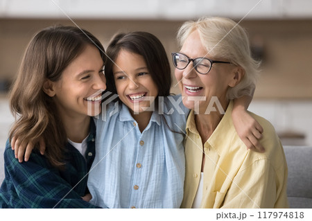 Happy child girl embracing beloved mom and grandma with love Happy child girl embracing beloved mom and grandma with love 117974818