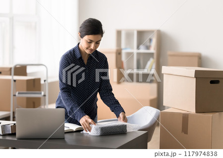 Indian woman packing bought goods working in warehouse Indian woman packing bought goods working in warehouse 117974838