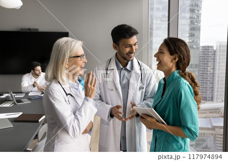 Older and younger doctors engaged in lighthearted conversation Older and younger doctors engaged in lighthearted conversation 117974894