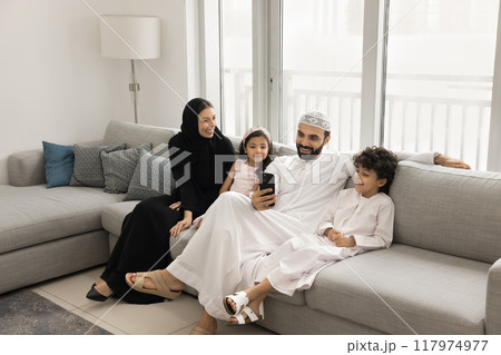 Happy Arabic parents and two little children using smartphone together Happy Arabic parents and two little children using smartphone together 117974977