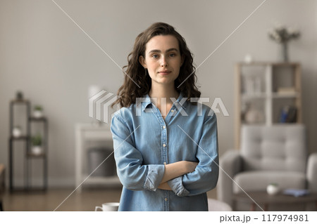 Serious woman standing in modern living room Serious woman standing in modern living room 117974981