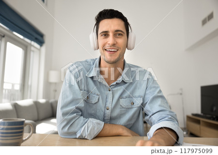 Happy handsome Hispanic professional man in headphones speaking at camera Happy handsome Hispanic professional man in headphones speaking at camera 117975099
