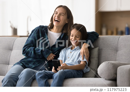 Happy excited young mother hugging adorable smart daughter kid Happy excited young mother hugging adorable smart daughter kid 117975223