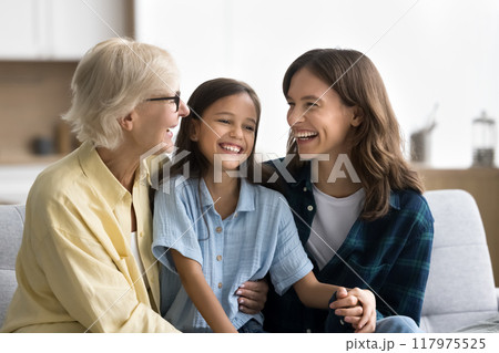 Joyful young mom and senior grandma cuddling kid girl 117975525