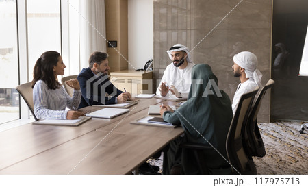 Happy young Arab business leader man talking to diverse partners 117975713