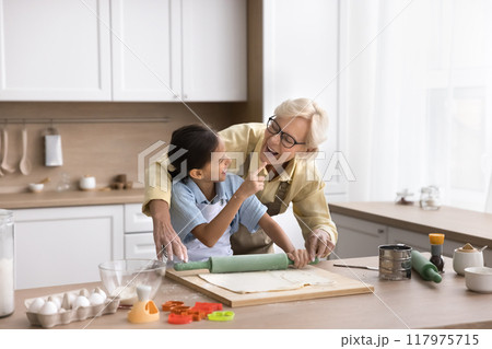 Playful cute granddaughter kid touching face of happy laughing grandma 117975715