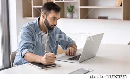 Focused handsome Latin business professional man working at laptop Focused handsome Latin business professional man working at laptop 117975773