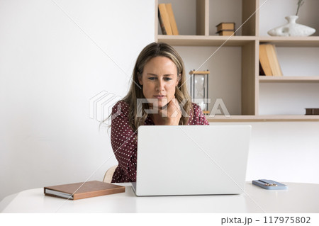 Positive manager woman focused on online content on screen Positive manager woman focused on online content on screen 117975802