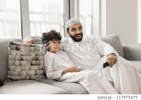 Cheerful Muslim father and positive son boy watching TV show Cheerful Muslim father and positive son boy watching TV show 117975875