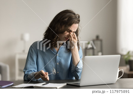 Tired woman feels eye strain after long usage of laptop 117975891