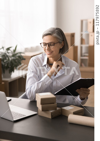Mature businesswoman, small business owner managing orders or logistics tasks Mature businesswoman, small business owner managing orders or logistics tasks 117975892